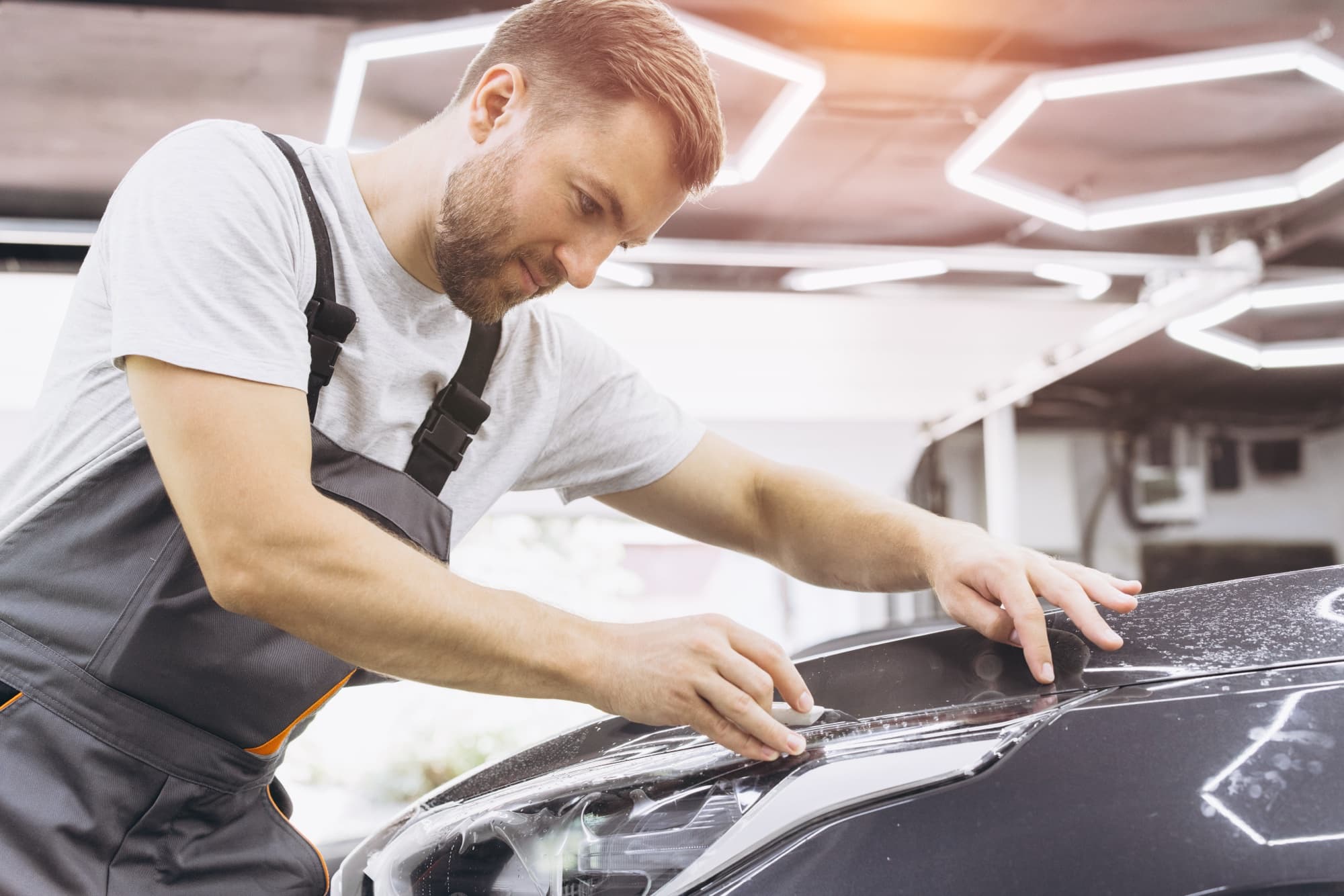 Professional car wrap installer applying vinyl film in a shop